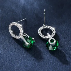 Macro de boucles d'oreilles argentées avec pierres vert émeraude et pavé de cristaux brillants