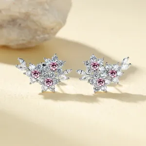 Close-up of pink flower stud earrings with marquise-cut zircons on a textured stone base
