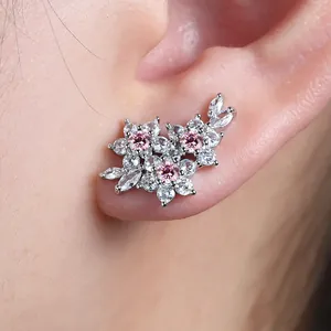 Detailed view of silver flower earrings with pink and white cubic zirconia on ear