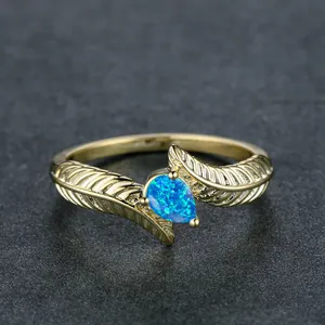 Detailed macro view of pear-shaped blue opal ring with gold feather textured band