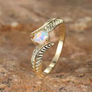 Detailed close-up of golden feather ring band featuring a teardrop-shaped opal stone
