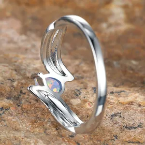 Silver feather ring with teardrop white opal set on natural stone background
