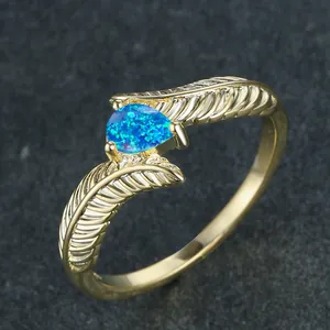 Luxurious gold feather ring with a pear-shaped blue fire opal stone set in wings