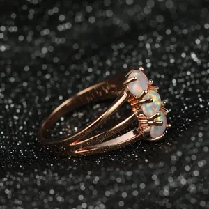 Macro détaillée d'une bague en or rose avec trois opales rondes et anneau à trois couches