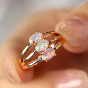 Bague opale à trois pierres en finition or rose avec anneau triple et gemmes irisées