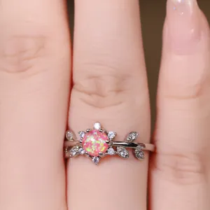 Détail macro d'une bague argentée avec opale rose et zircons en forme de feuilles sur main