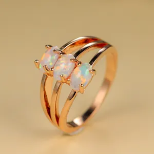 Détail d'une bague triple en or rose avec trois opales de feu ovales serties à griffes