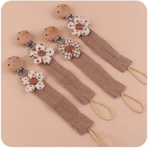 Detail of four baby pacifier clips made of beech wood and floral cotton linen straps