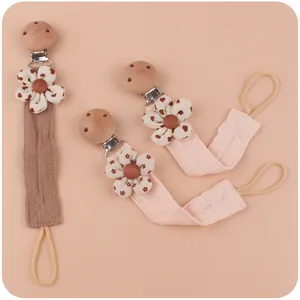 Detail of wooden pacifier clips with cotton fabric straps and floral appliques