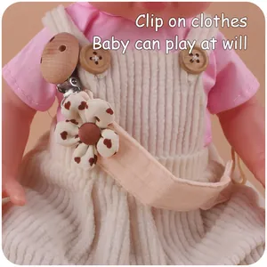 Macro shot of a floral cotton pacifier clip with beech wood clasp attached to baby clothes