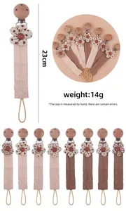 Detail view of cotton pacifier clip with beech wood grip and floral fabric textures