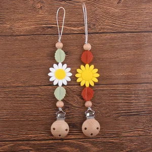 Attache-tétine en bois de hêtre et silicone tournesol sur fond de bois sombre