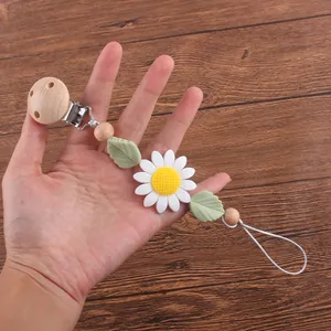 Attache-tétine en bois de hêtre et silicone tournesol avec feuilles vertes sur bois
