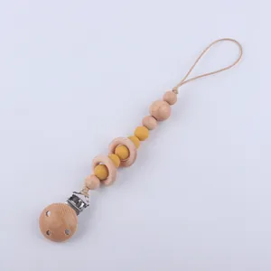 Détail de l'attache-tétine avec anneaux en bois de hêtre et perles en silicone jaune