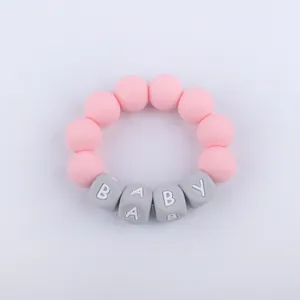 Macro shot of pink and grey silicone baby teething bracelet with square letter beads
