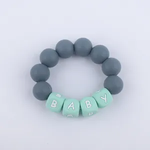 Macro detail of silicone baby teething bracelet with grey beads and mint green BABY letters