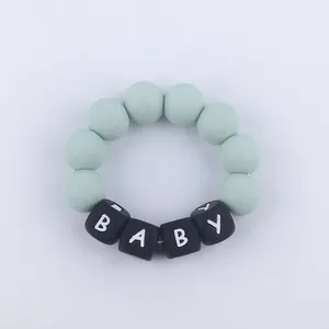 Macro shot of green silicone teether bracelet with BABY letter beads for infant teething