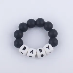 Detail of baby teething bracelet with black silicone beads and white BABY letter cubes