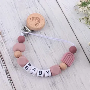 Detail eines hölzernen Regenbogen-Schnullerkettenhalters mit Silikonperlen und BABY-Schriftzug