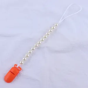 Detail of baby pacifier clip with orange plastic buckle and white pearl beads