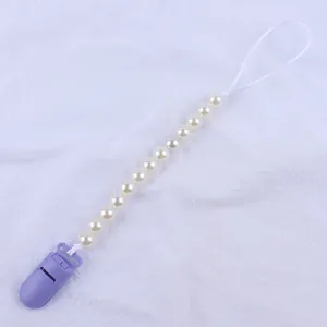 Detail of baby pacifier clip featuring purple plastic clasp and imitation pearl beads