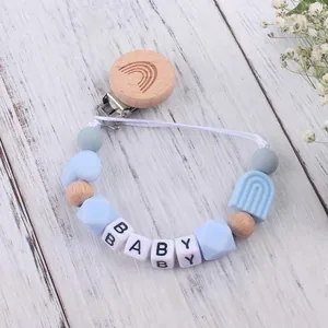Detail eines hölzernen Regenbogen-Schnullerkettenhalters mit Silikonperlen und BABY-Buchstaben
