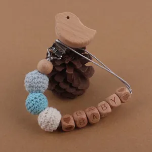 Détail de l'attache-tétine bébé en bois avec perles tricotées et perles lettres BABY