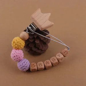 Détail du clip couronne en bois et perles alphabet sur une attache-tétine au crochet