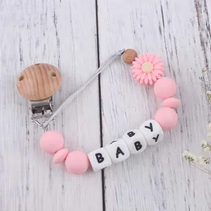 Close-up of pink daisy silicone pacifier clip with wooden beads and baby letters