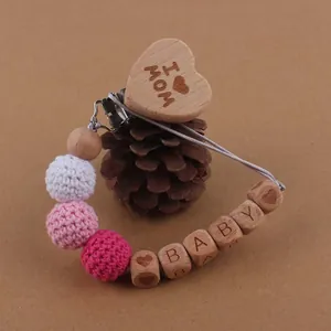 Détail de l'attache-tétine en bois avec boules au crochet et gravure I Love Mom