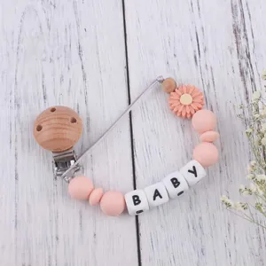 Daisy silicone teether pacifier clip with baby letter beads on white wood surface