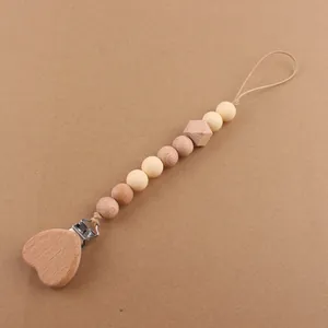 Detail of baby pacifier clip with beech wood heart clamp and cream silicone beads