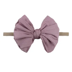 Détail d'un bandeau pour bébé en tissu côtelé avec grand nœud violet et nylon élastique