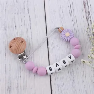 Close-up of lavender daisy silicone pacifier clip with BABY letters and wooden clip