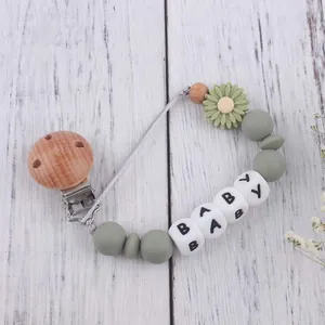 Detailed view of silicone baby pacifier clip with green daisy and wooden beads