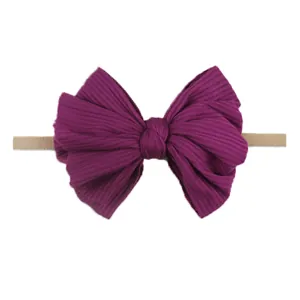 Détail d'un bandeau bébé en maille violette avec un grand nœud et une bande élastique