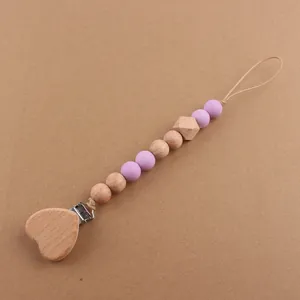 Detail of wooden heart clip and purple silicone beads on a natural baby pacifier chain