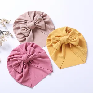 Three-piece set of baby turban hats with large bows in pink and yellow ribbed knit