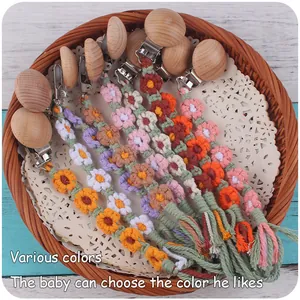 Détail d'attache-tétine en hêtre fait main avec chaîne de fleurs tissées et glands colorés