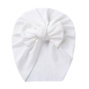 Close-up of white ribbed knit fabric texture and bow detail on the baby turban hat