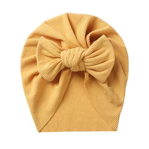 Detailed texture of ginger yellow ribbed baby turban hat with a large bow decoration
