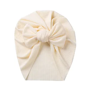 Detailed view of the ribbed knit fabric and large decorative bow on the cream baby turban hat