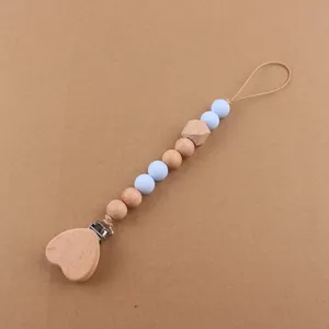 Detail of baby pacifier clip with beech wood heart and light blue silicone beads