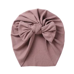 Close-up of baby turban hat featuring mauve ribbed knit fabric and large bow detail