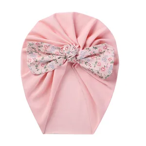 Detailed view of pink baby turban hat featuring a soft floral pattern bow decoration