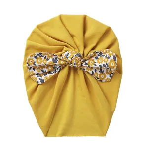 Detail of baby turban hat in mustard yellow with floral bow in soft jersey knit