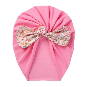 Detail of baby turban hat with a large floral bow on soft pink knit cotton fabric