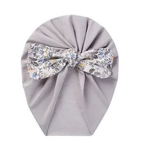 Detail of baby turban hat featuring a large floral bow on soft purple-grey fabric