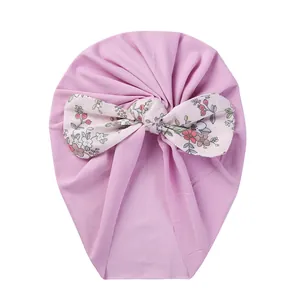 Detail of baby pink turban hat featuring a large floral bow with berry patterns