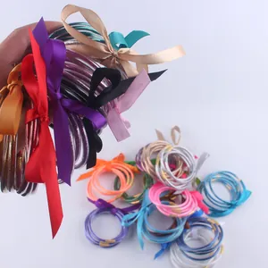 Dettaglio di bracciali in silicone glitterato con fiocchi di nastro in raso coordinati